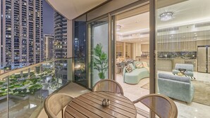 Un appartement moderne doté d’un balcon donnant sur le paysage urbain, d’un coin repas avec des meubles en osier et d’une cuisine équipée d’appareils électroménagers en acier inoxydable.