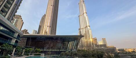 A modern hotel with a pool, surrounded by high-rise buildings and palm trees.