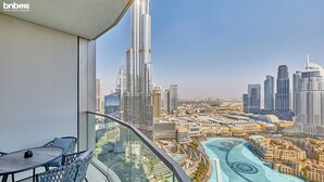Un balcon doté d’une balustrade en verre, offrant une vue sur un paysage urbain avec des gratte-ciel modernes et une zone riveraine.