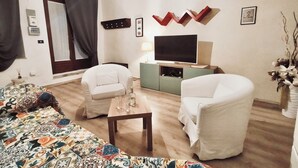 A living room with a sofa, two chairs, a coffee table, a TV, and a decorative wall piece. - La Casetta sul Lago (Viverone)