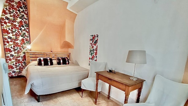 A bedroom with a bed, bedside table, lamp, chair, and a radiator. - La Casetta sul Lago (Viverone)