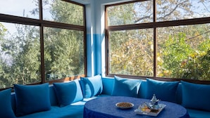A room with a blue sofa and a round table with a tray of food and drinks. - Dar Assounfou (Aït Majden)