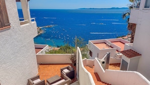 A rooftop terrace with a view of the sea, outdoor furniture, and a staircase. - House in Rosas With Waterfront & Beach Nearby (Roses)