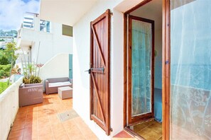 An outdoor balcony with a wooden door, a cushioned seating area, and a view of the surrounding buildings. - House in Rosas With Waterfront & Beach Nearby (Roses)