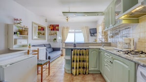 A compact kitchen with a dining area, a sofa, and a TV mounted above the counter. - House in Rosas With Waterfront & Beach Nearby (Roses)