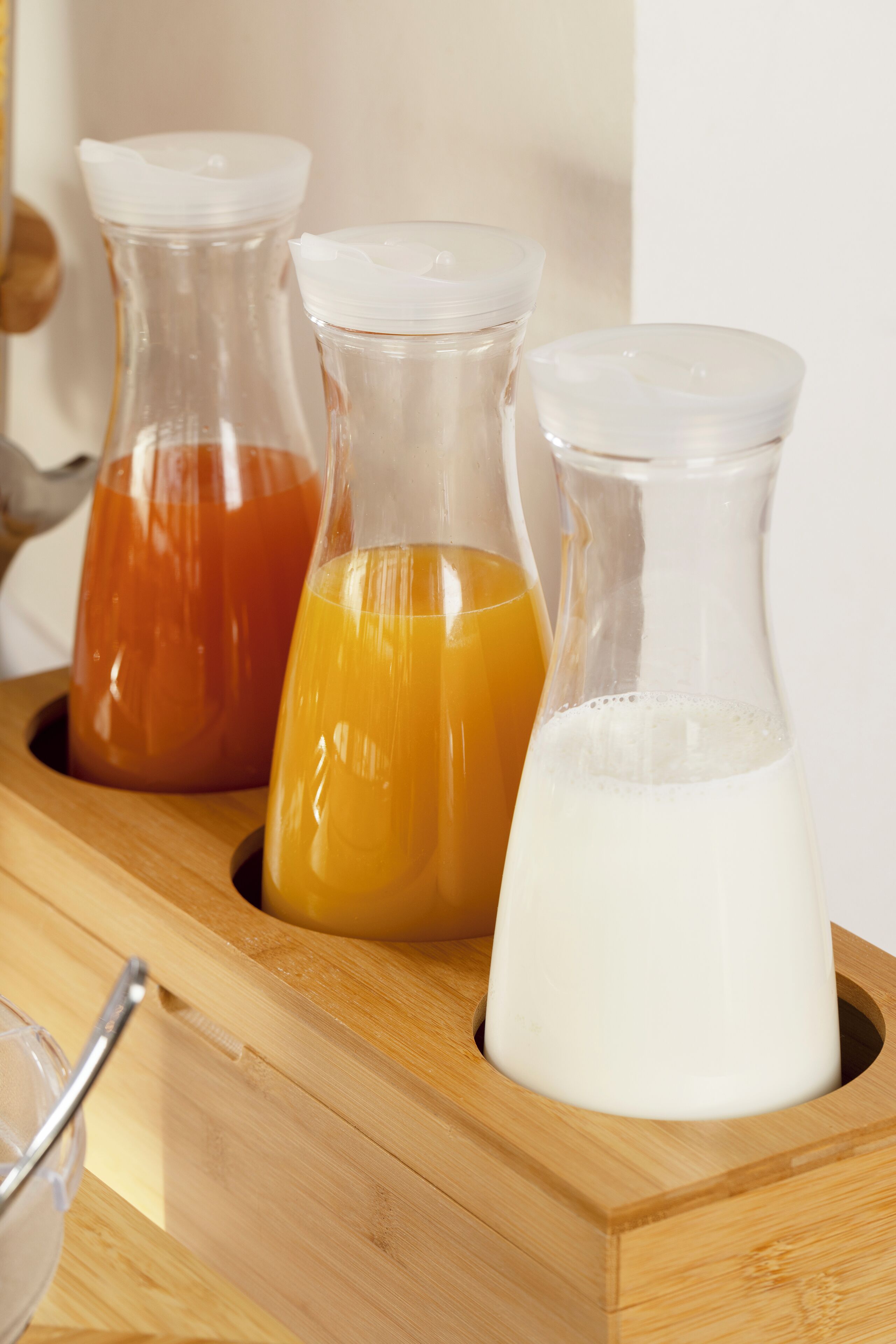 Three glass containers with different liquids on a wooden tray.