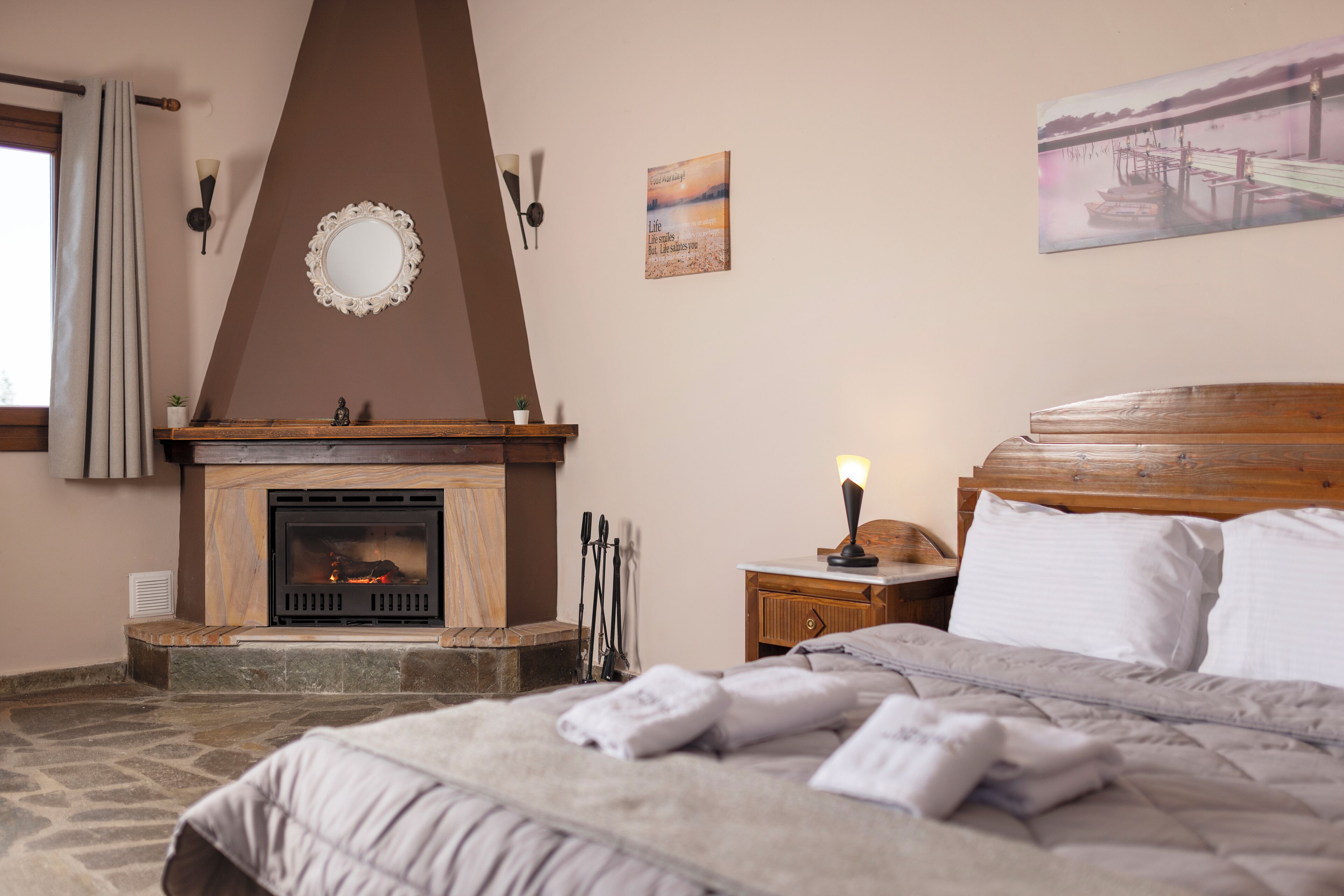 Un dormitorio con chimenea, una cama con ropa de cama blanca y un cuadro en la pared.