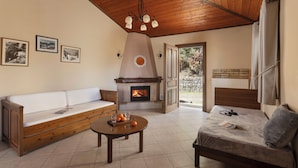 A cozy living room with a wooden ceiling, a fireplace, a sofa, a coffee table, and a bed. - Ktima Alonaki (Lake Plastiras)