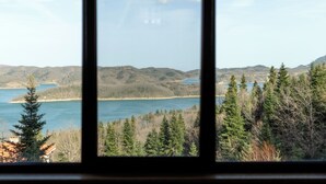 A view through a window of a mountainous landscape with a lake and dense forest. - Ktima Alonaki (Lake Plastiras)