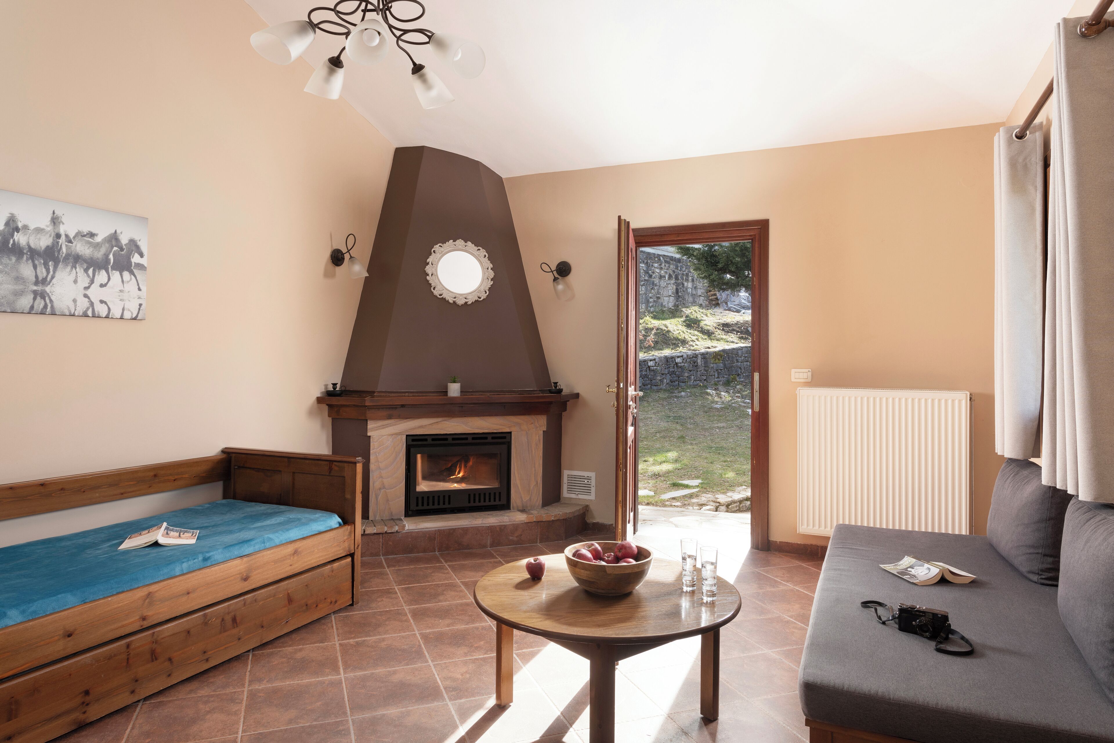 A cozy living room with a fireplace, a sofa, a wooden bench, and a table with a bowl and glasses.