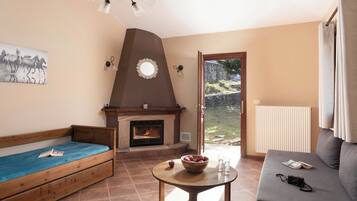 A cozy living room with a fireplace, a sofa, a wooden bench, and a table with a bowl and glasses.