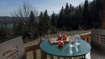 Una mesa con una tabla de madera, dos granadas y tres vasos de agua.