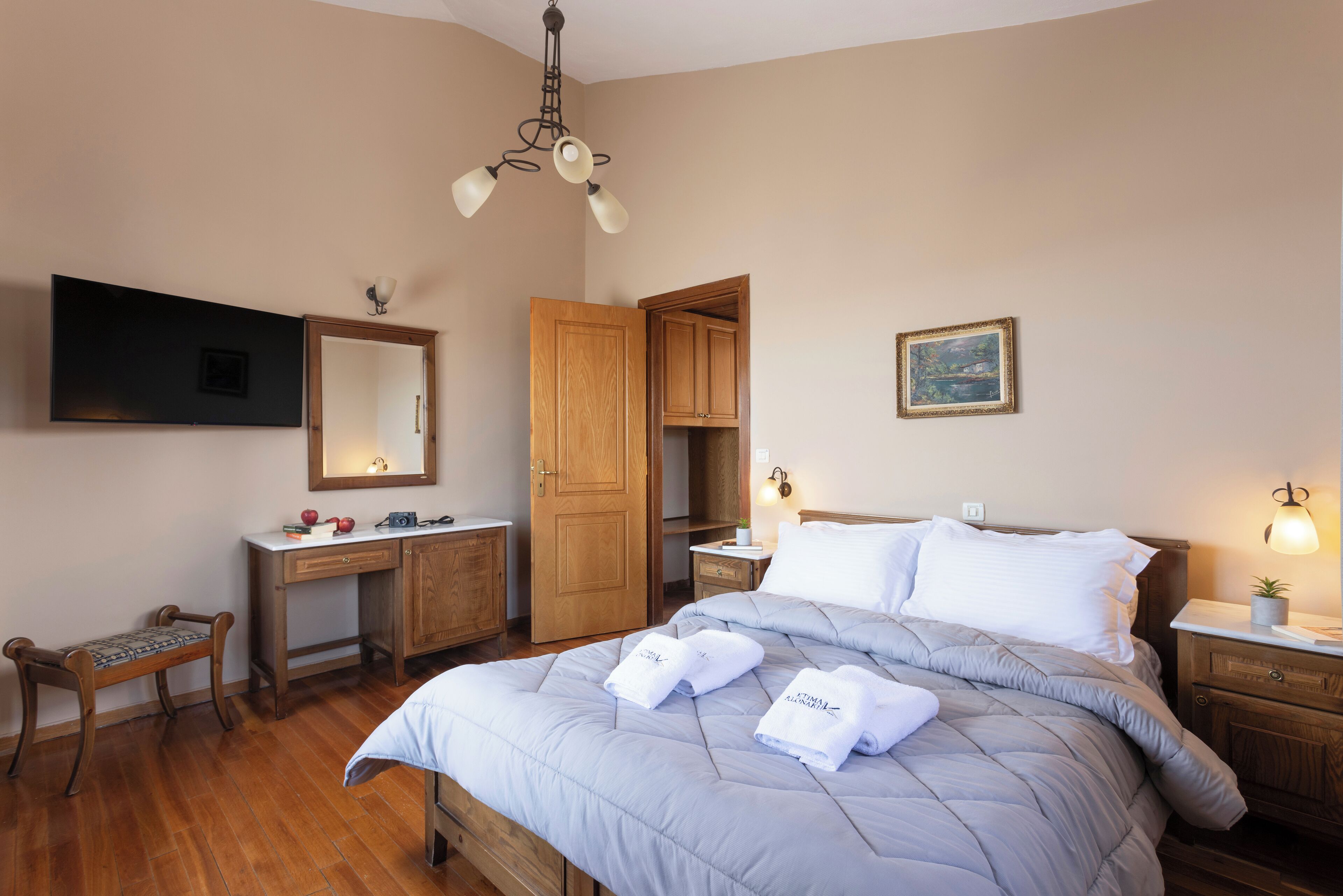 A bedroom with a bed, bedside tables, a desk, a chair, a wardrobe, a mirror, and a ceiling light fixture.