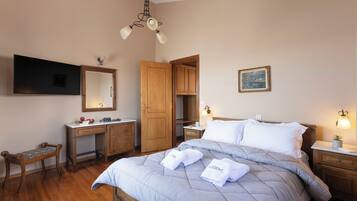 A bedroom with a bed, bedside tables, a desk, a chair, a wardrobe, a mirror, and a ceiling light fixture.