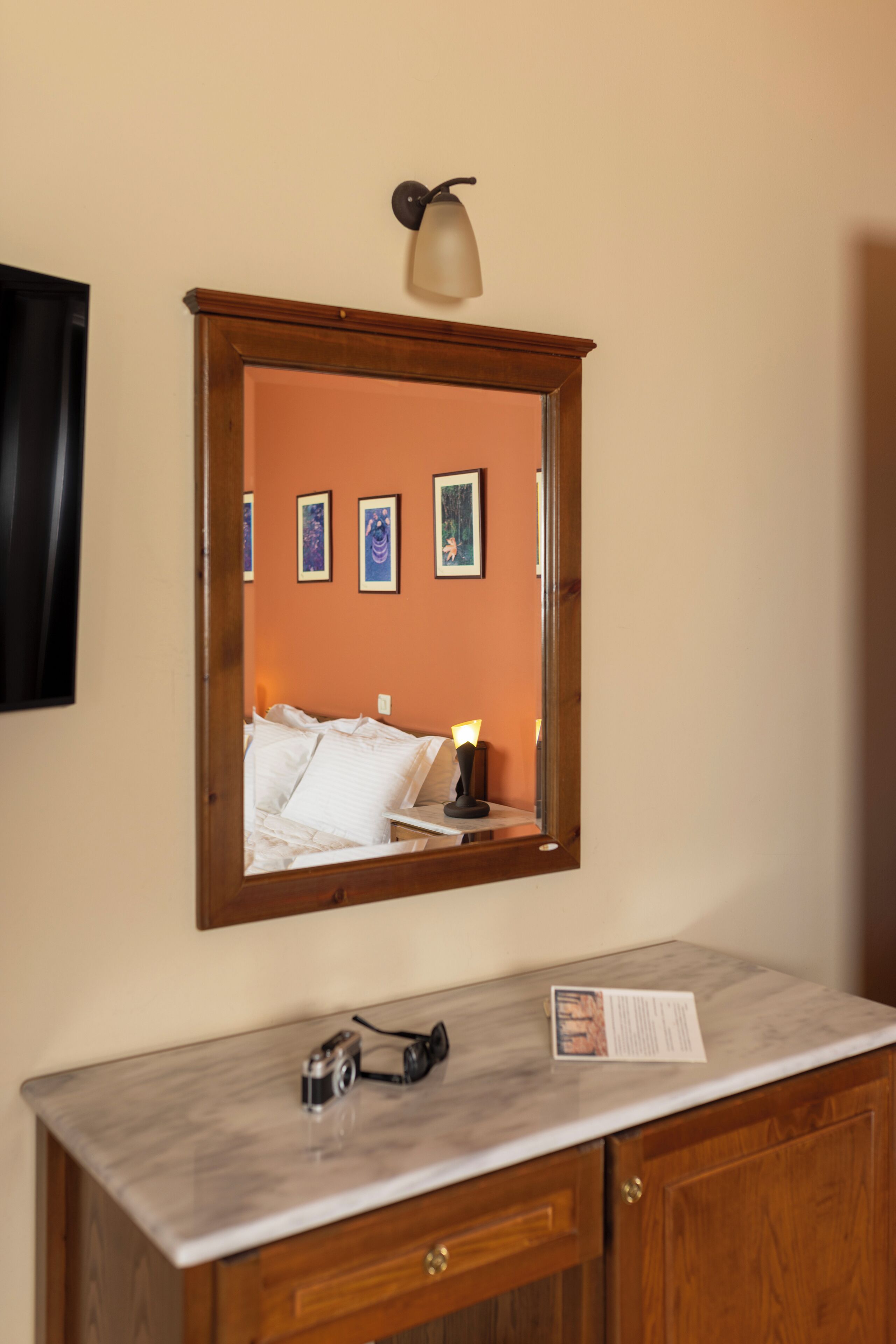 A bathroom with a wooden vanity, a mirror, and a framed picture on the wall.