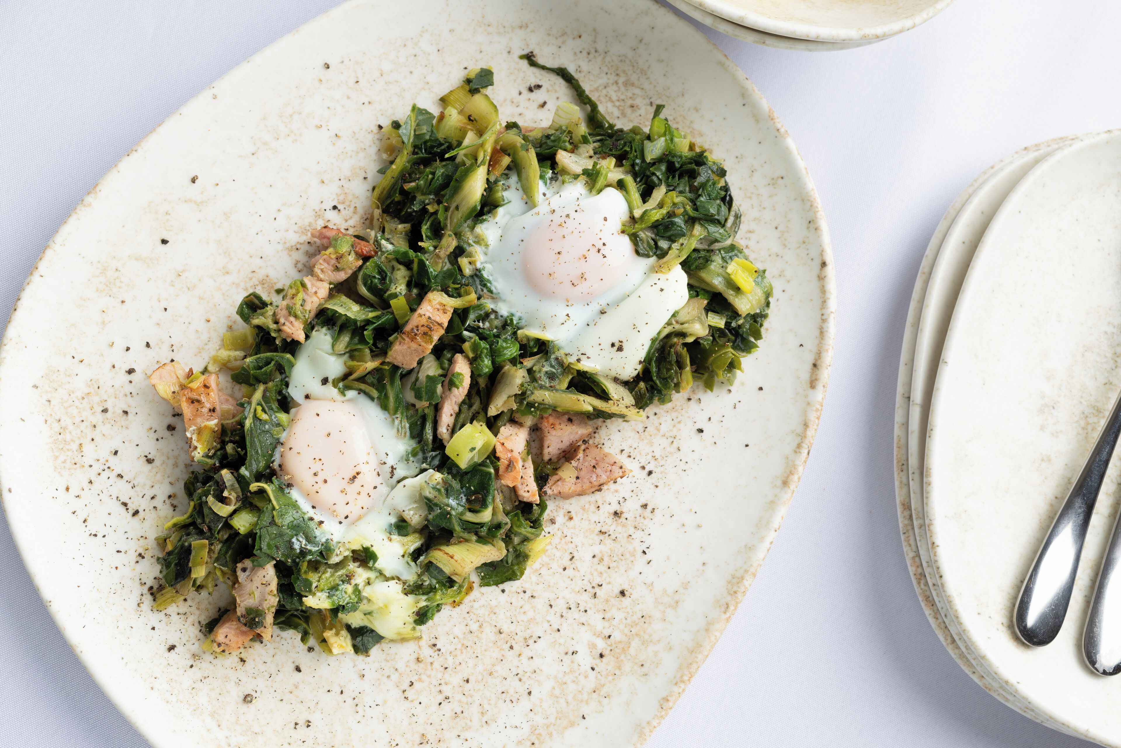Une assiette de nourriture comprenant des légumes verts, des œufs et de la viande.