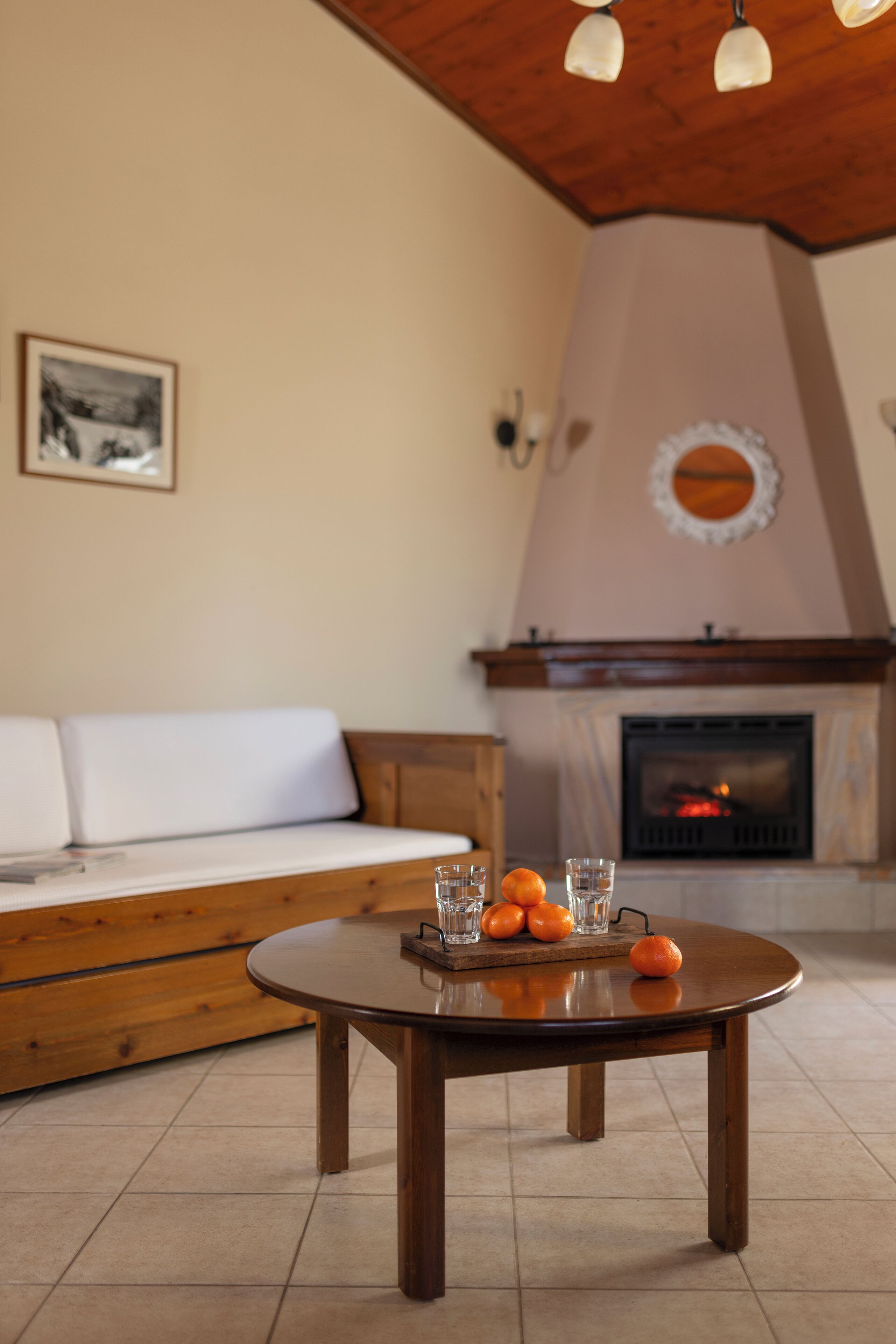 Una sala de estar acogedora con una mesa redonda de madera, un sofá blanco y una chimenea.