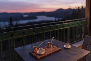 A table with two cups of coffee and a small pot on a wooden tray, set against a scenic mountain view. - Ktima Alonaki (Lake Plastiras)