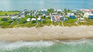 An aerial view of a coastal area with buildings, a beach, and a body of water. - Waterfront | Fishing Pier | Walk to Beach (Cocoa Beach)