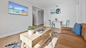 A living room with a wooden coffee table, a brown sofa, and a small table with chairs. - Waterfront | Fishing Pier | Walk to Beach (Cocoa Beach)