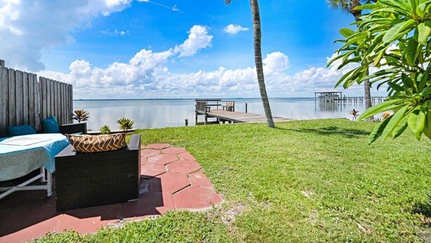 A patio with outdoor furniture, a palm tree, and a view of the water. - Waterfront | Fishing Pier | Walk to Beach (Cocoa Beach)