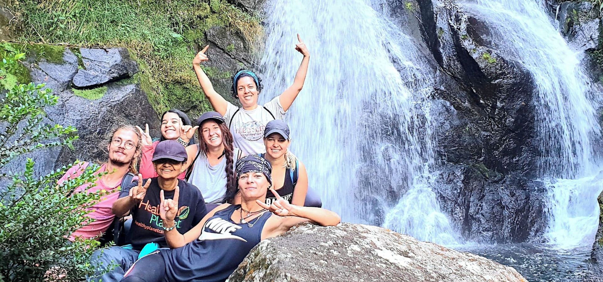 A group of people posing in front of a waterfall.