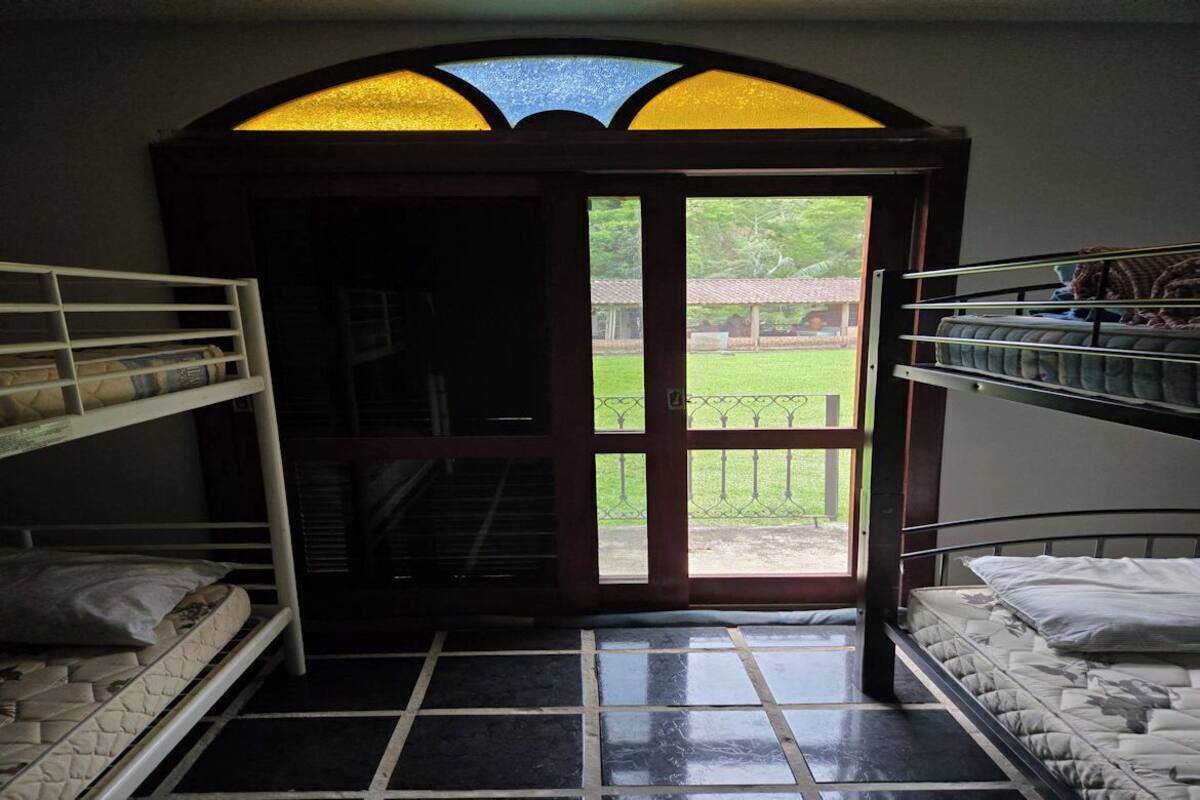 Una habitación con literas, un amplio ventanal de arco y vistas a un paisaje verde.