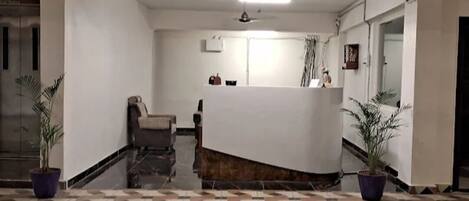 A reception area with a curved reception desk, a chair, and potted plants.