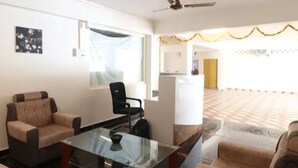 Amplia sala de estar con una mesa de centro de vidrio, dos sofás, un ventilador de techo y vistas de un piso de baldosas y una puerta al fondo.