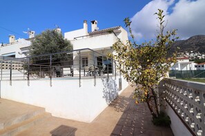 A white building with a balcony, steps leading up to it, and a tree with yellow leaves. - Beautiful Apartment With View (Roses)