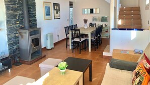 A living room with a stone wall, a fireplace, a dining area, and a staircase. - Beautiful Apartment With View (Roses)
