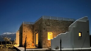 A stone building with a modern design, featuring a staircase leading to a door with a lit interior. - Quiet house in southern Crete, picturesque sea and mountain views, beach within walking distance (Pitsidia)