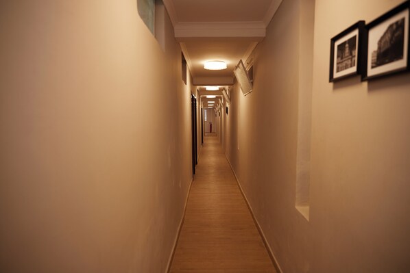A narrow hallway with wooden flooring and white walls, leading to a door at the end. - Hotel King's Palace (Lubumbashi)