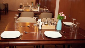 Una mesa de comedor lista con platos, cubiertos y un jarrón de flores.