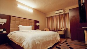 Habitación de hotel con una cama grande, un escritorio, una silla y un televisor.