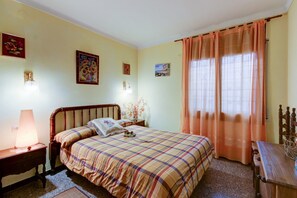 A bedroom with a bed, nightstand, lamp, and a wooden table. - Apartment in Roses by the Beach & Marina (Roses)