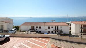 A coastal building with a tiled roof, a parking area, and a view of the sea. - Apartment in Roses by the Beach & Marina (Roses)