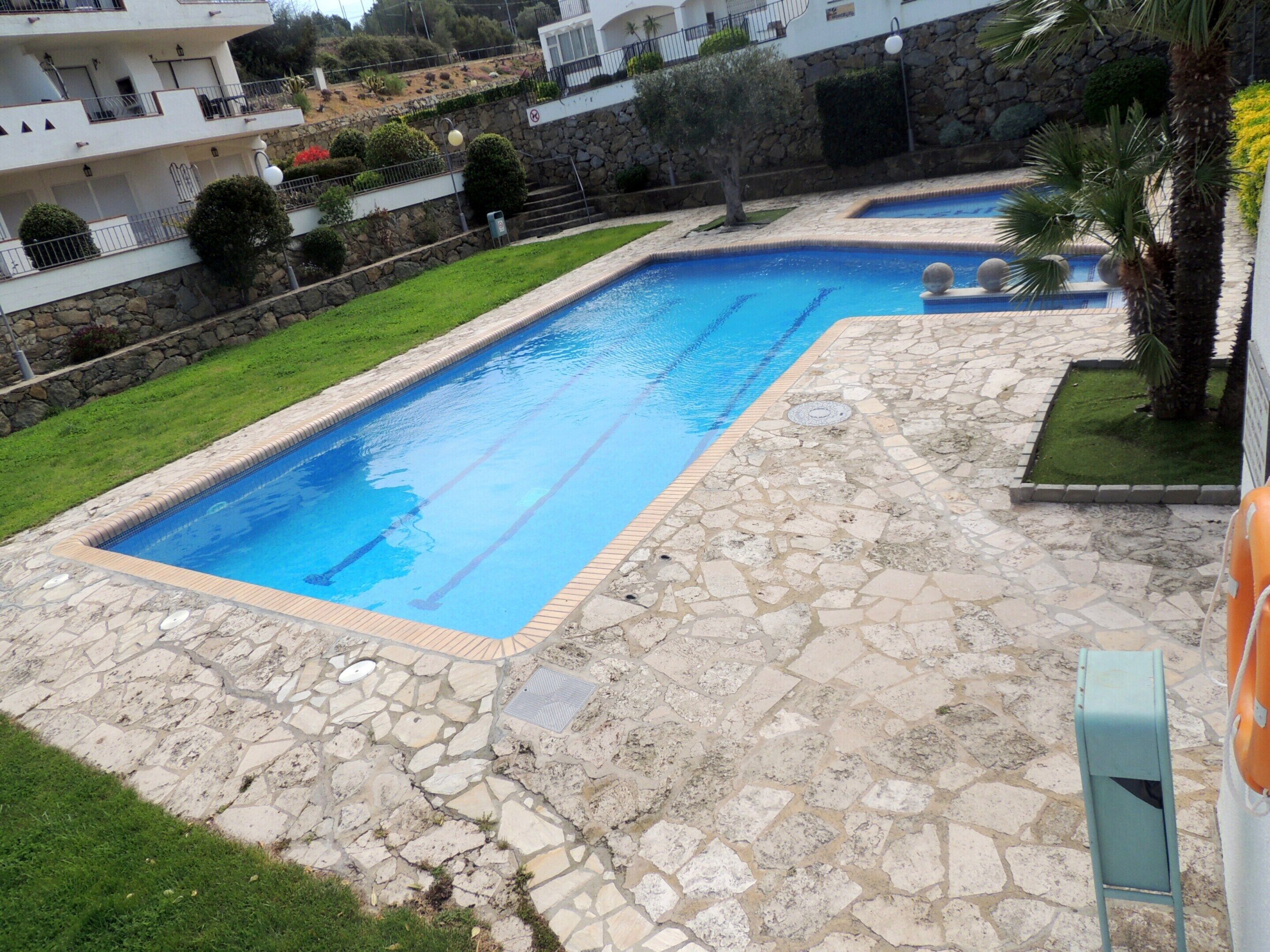 Ein Pool mit Steinfliesen und einer Steinwand.