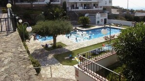 A residential building with a swimming pool, surrounded by greenery and a stone pathway. - Apartment by Roses Beach With Pool (Roses)