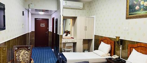 Une chambre d’hôtel avec deux lits, un bureau, une chaise et un appareil de climatisation.