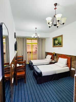A hotel room with two beds, a large mirror, a chandelier, and a painting on the wall.