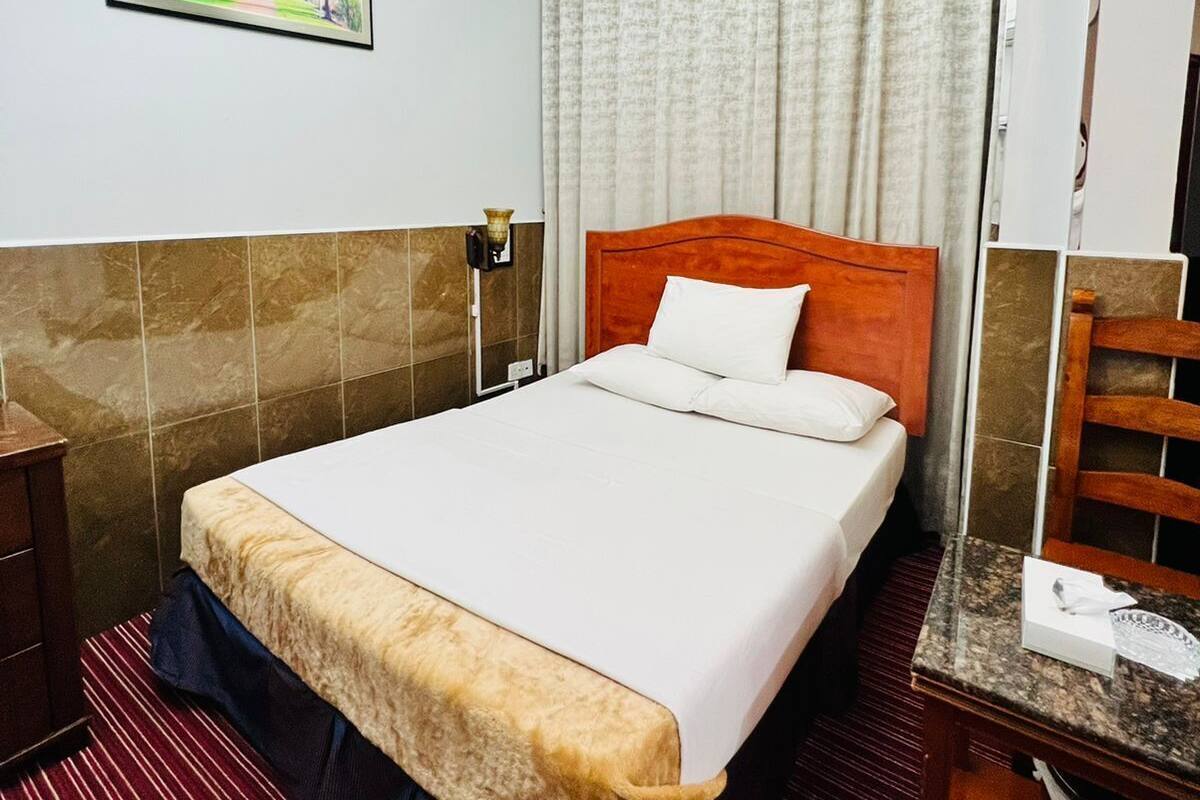 A hotel room with a bed, a nightstand, a mirror, a chandelier, and a painting on the wall.