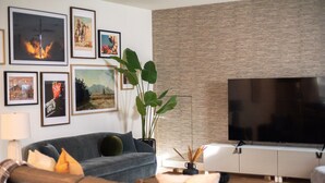 Una sala de estar moderna con un sofá gris, un televisor de pantalla plana y obras de arte enmarcadas en la pared.