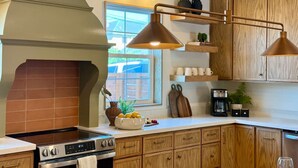 Una cocina con gabinetes de madera, estufa e iluminación colgante.