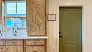 Una cocina con armarios de madera, una ventana con vistas y una puerta verde.