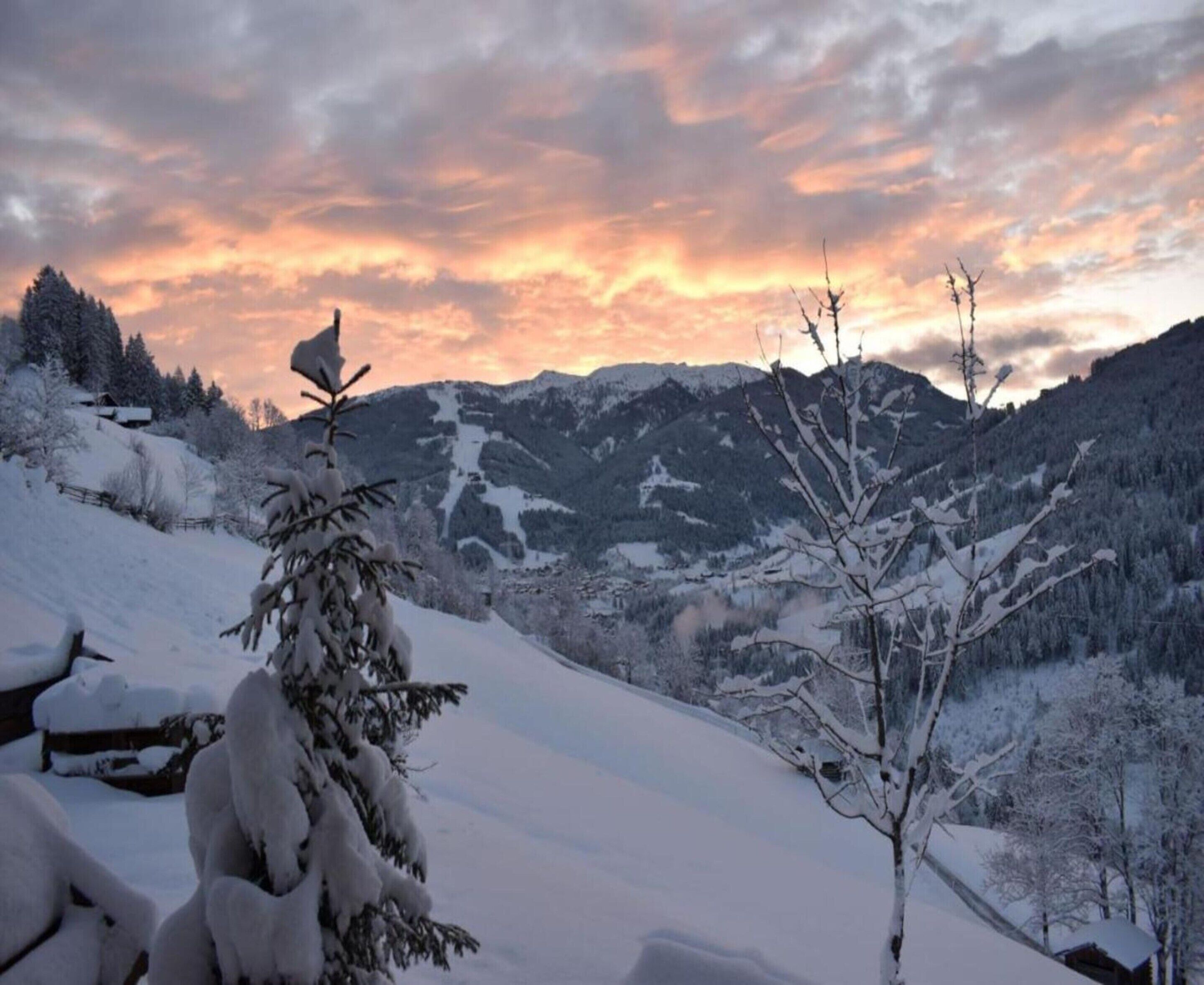 A snowy mountain landscape with a sunset sky.