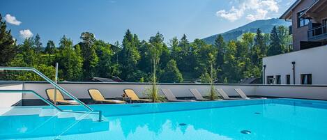 A swimming pool with lounge chairs and a mountain backdrop.