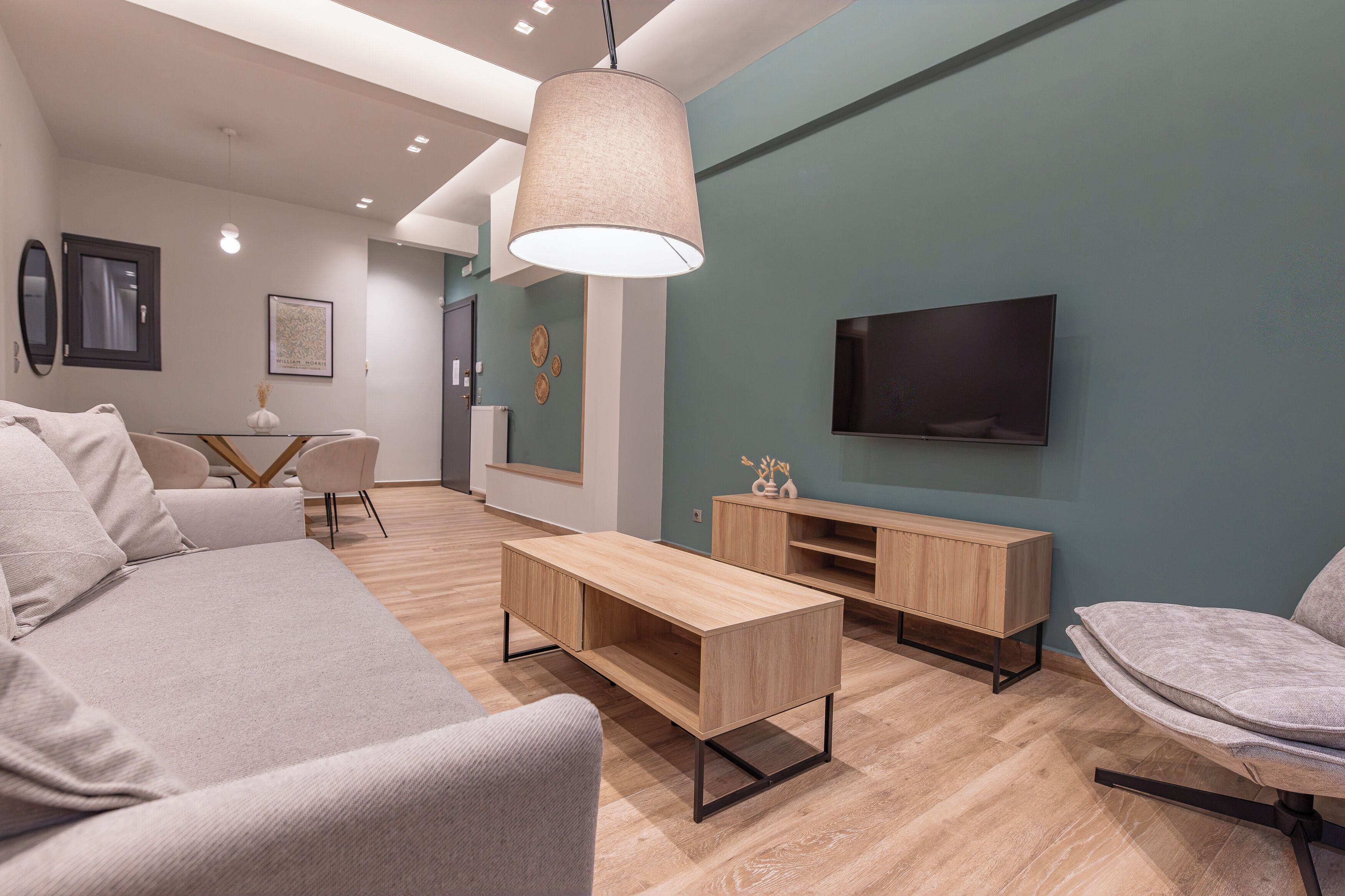 A modern living room with a sofa, coffee table, TV, and wooden furniture.