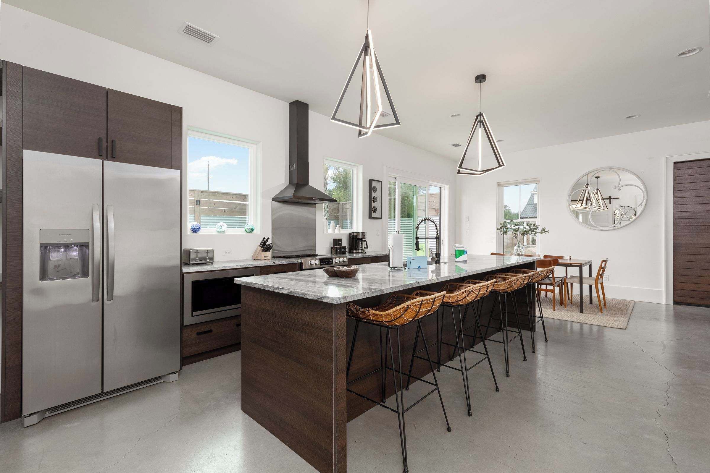 A modern kitchen with a central island, stainless steel appliances, and pendant lighting.