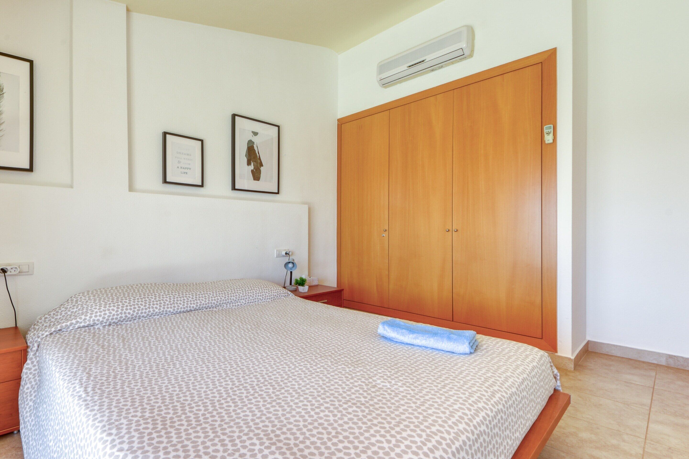 A bedroom with a bed, a wardrobe, and two framed pictures on the wall.
